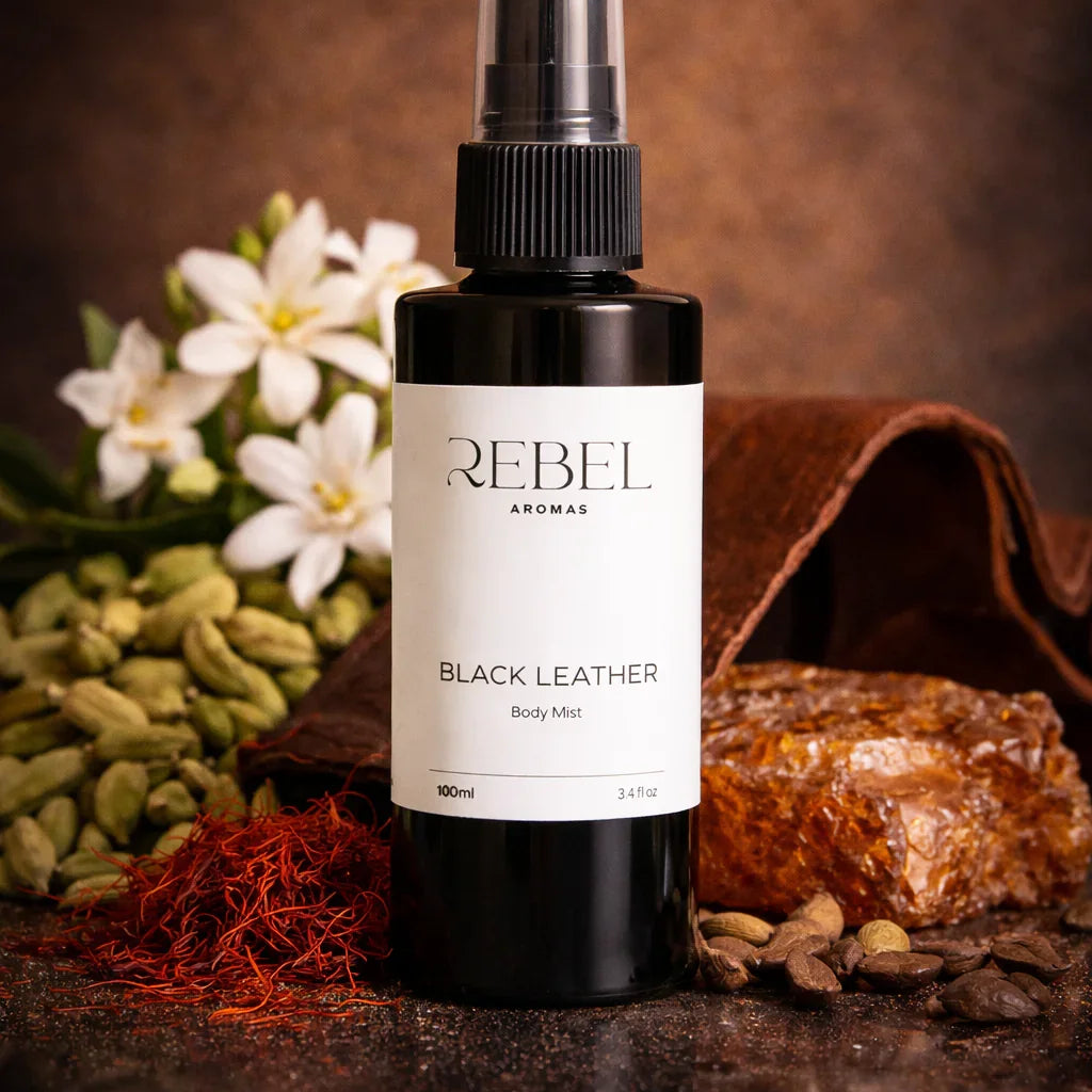 Black leather body mist bottle labeled 'REBEL' with flowers and a leather pouch in the background.