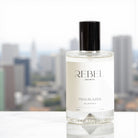 Bottle of Rebel Aromas Trailblazer perfume with a cityscape in the background