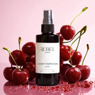 Bottle of Rebel Aromas Cherry Temptation Body Mist surrounded by cherries on a pink background