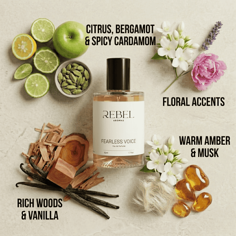 Perfume bottle labeled 'Rebel Aromas Fearless Voice' surrounded by fruits, flowers, and wood elements on a textured surface.